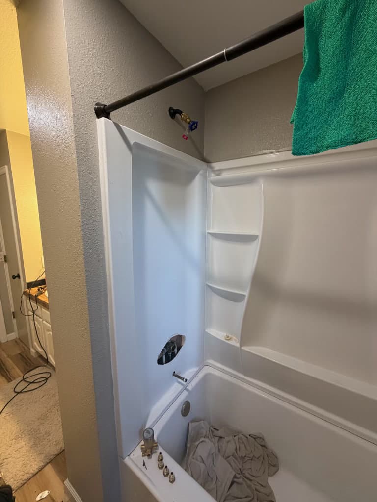 Before: shower and tub missing trim and shower head awaiting valve replacement — Northern Colorado bathroom plumbing