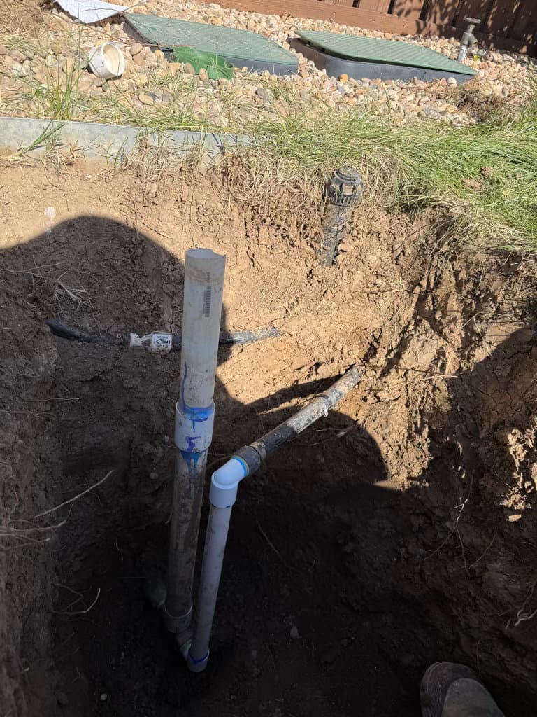 During: new PVC sewer lateral and fittings in excavated yard trench — sewer line replacement Northern Colorado
